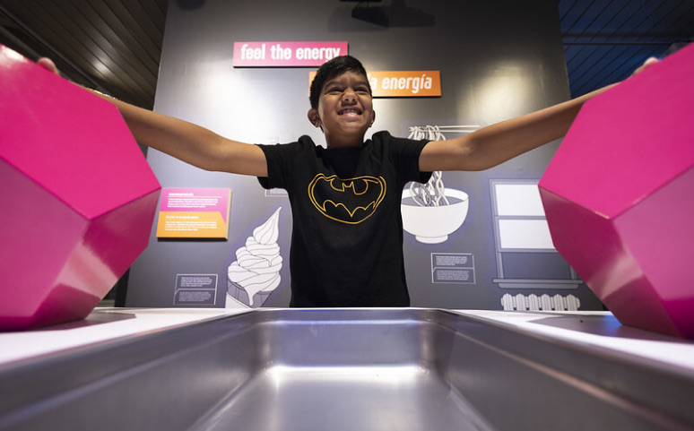 A picture of a student discovering the community science museum's powering the city exhibition.